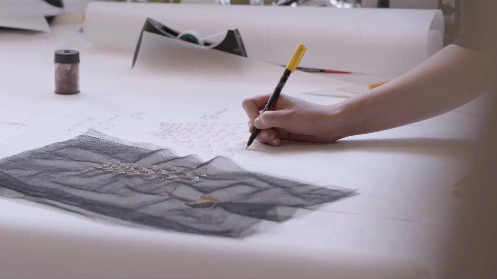 パターン用紙に指示を書き込む手元と、刺繍を施したチュールの生地